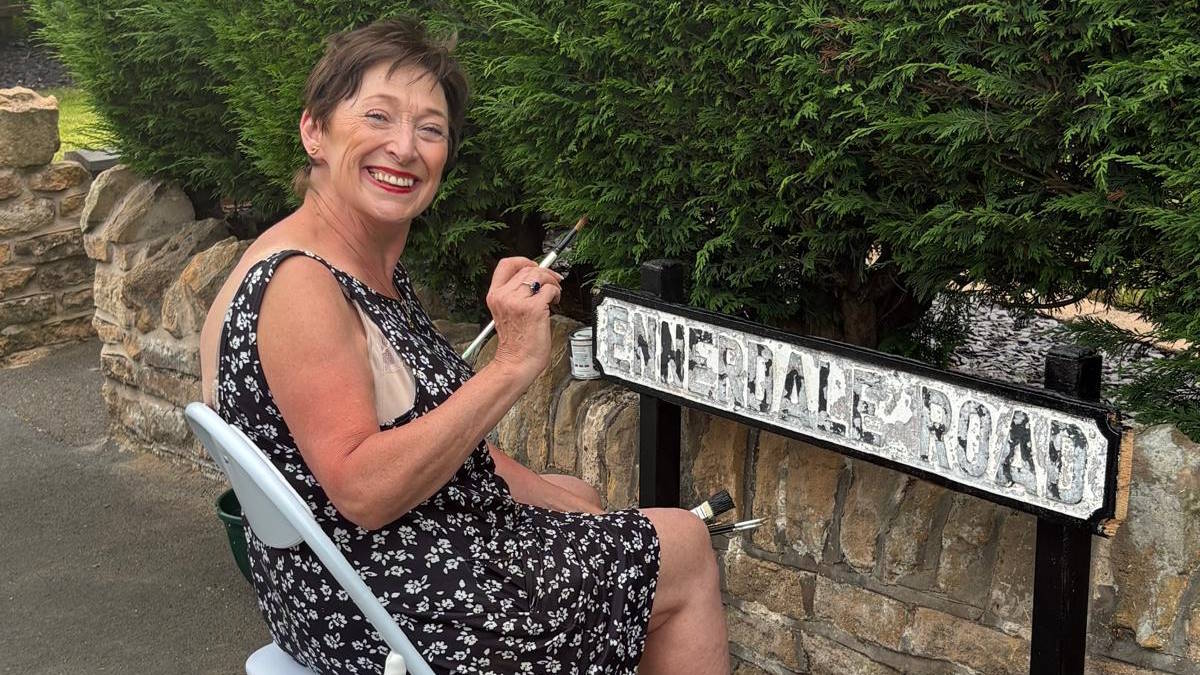 Ennerdale Road resident Glenda Templeton giving the street sign a much needed lick of black paint
