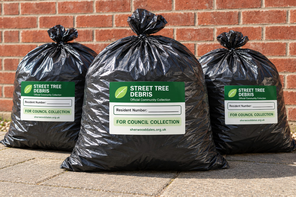 Three black bags of council street-tree debris with collection labels attached, ready for collection